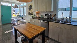 A modern kitchen with wooden cabinets, a stainless steel sink, and pendant lighting.