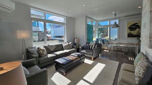 A spacious living room with a sofa, ottoman, and a dining area with chairs and a table.