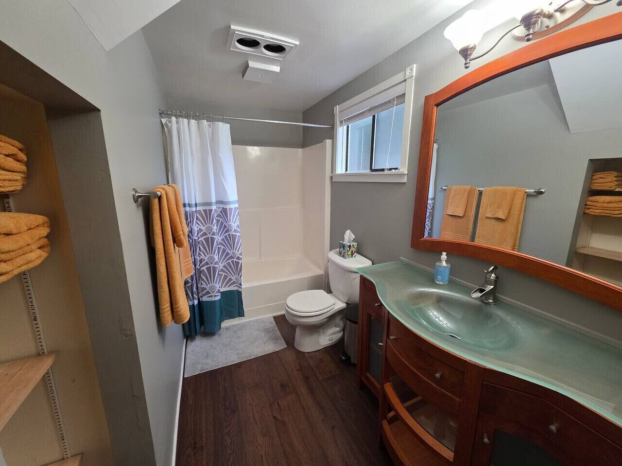 Et badeværelse med vask, toilet, brusebad og spejl.