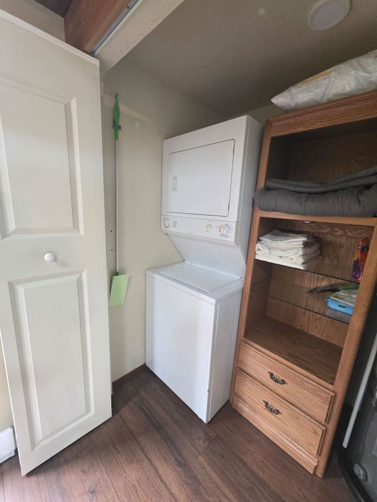 A compact laundry room with a washing machine, a dryer, and a wooden cabinet with folded clothes.