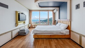 Habitación de hotel con una cama grande, televisor, vista de la ciudad y balcón.