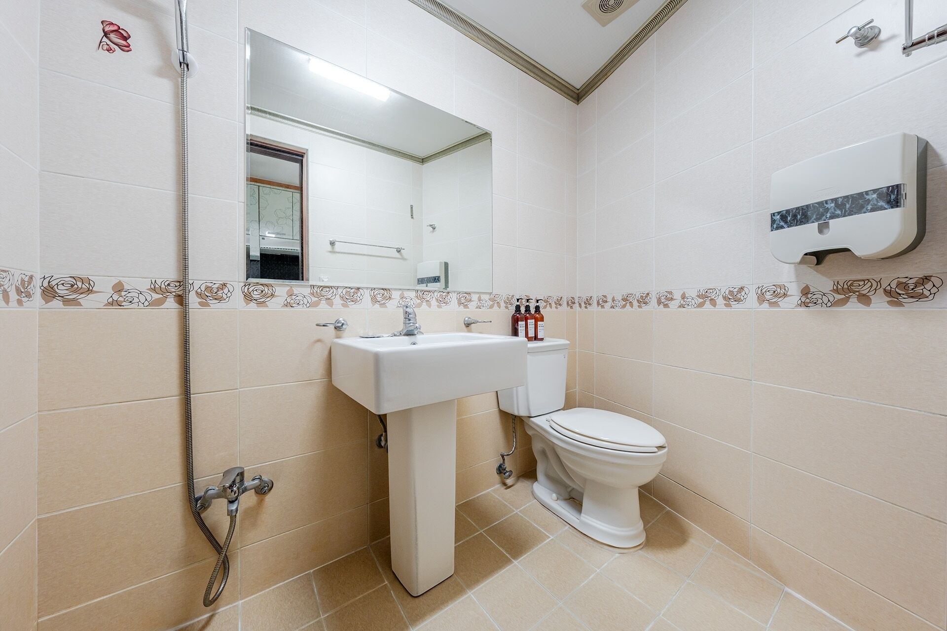 Une salle de bain équipée d’un lavabo, de toilettes, d’une douche et d’un sèche-mains.