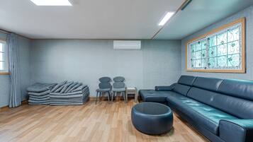 Un salon moderne avec un canapé, un pouf, des fauteuils et une pile de couvertures pliées.