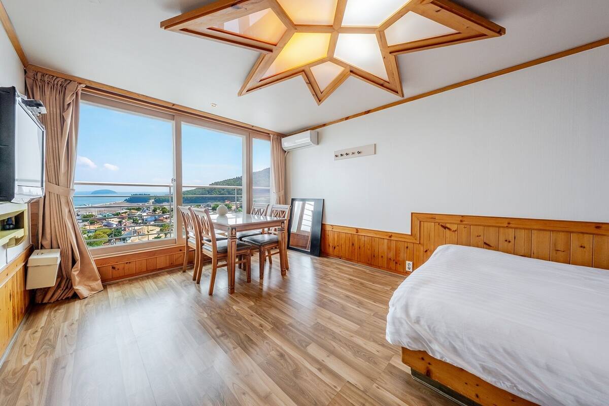 A bedroom with a large window, wooden furniture, a bed, and a star-shaped ceiling light fixture.