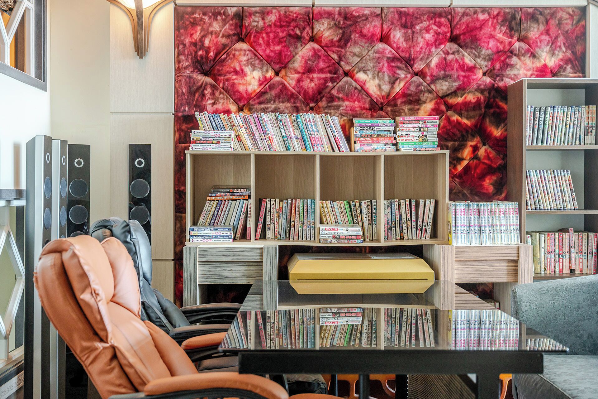 Une pièce avec une bibliothèque remplie de livres, un fauteuil en cuir et un mur décoratif.