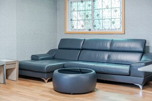 A modern living room with a sectional sofa, a round ottoman, and a wooden side table.