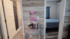 Une pièce avec une horloge, un lit, un bureau avec des livres et une plante en pot.