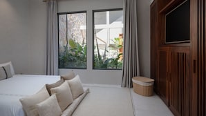 Ein Schlafzimmer mit einem Bett, einem Fernseher und einem Fenster mit Vorhängen.