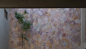 Eine Hängematte in einem Gartenbereich mit einer Steinmauer im Hintergrund.