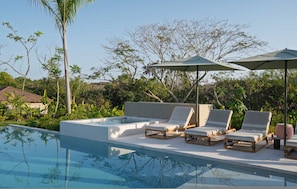 A pool area with lounge chairs and umbrellas, surrounded by greenery. - Villa Selva 33 in Punta Mita (Punta de Mita)