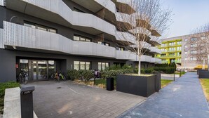 Un edificio moderno con diversi balconi, un vialetto lastricato e biciclette parcheggiate all'esterno.