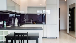 Una cucina moderna con mobili bianchi, un piano di lavoro nero e un'area pranzo con tavolo e sedia neri.