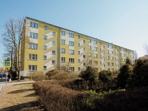A multi-story building with a distinctive zigzag pattern on the facade, a pedestrian crossing sign, and a clear sky. - Fałata Comfort Apartment (Toruń)