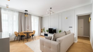 Un salon moderne comprenant un canapé, une table à manger, des chaises, un téléviseur et un coin cuisine.