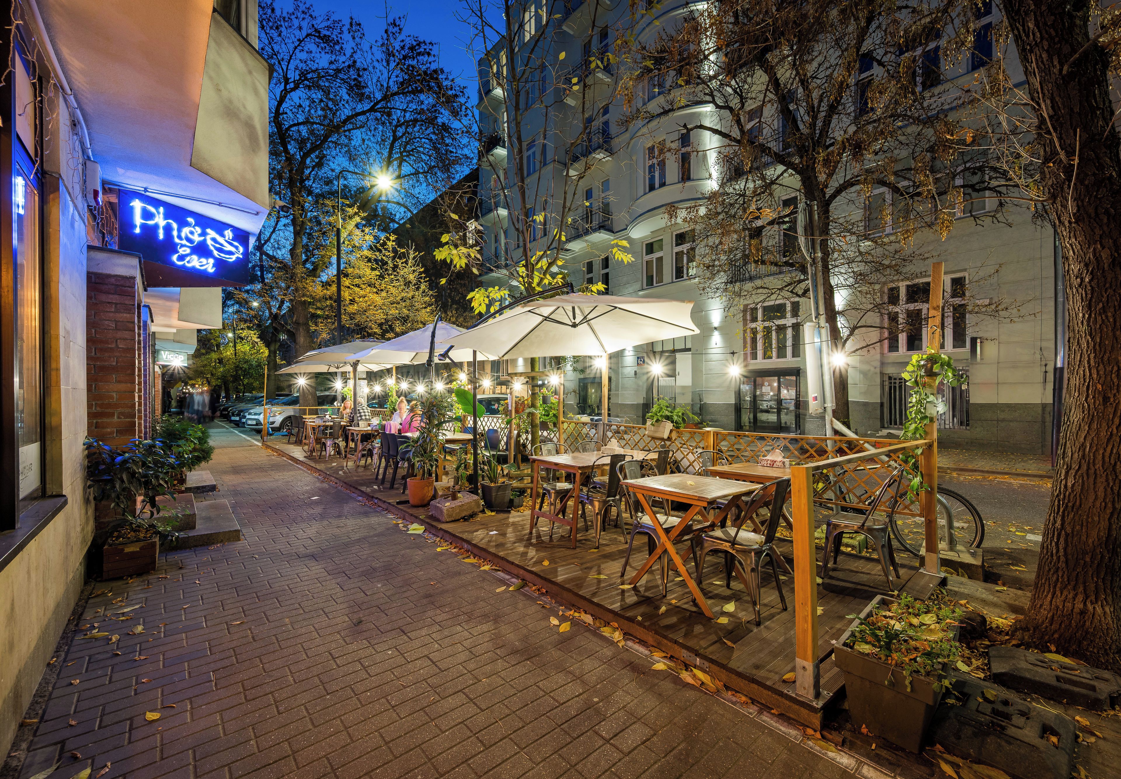 An outdoor café with tables and chairs, surrounded by trees and buildings.