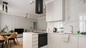 Une cuisine moderne avec des meubles blancs, un lave-vaisselle noir et un coin repas comprenant des chaises et une table en bois.