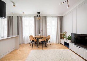 Une cuisine moderne avec un coin repas, un téléviseur à écran plat et une grande fenêtre avec des rideaux.
