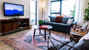 Un salon comprenant une télévision, un canapé, un fauteuil, une table basse et un tapis.