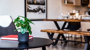 Un coin repas avec une table ronde, une plante en pot et un livre rouge.