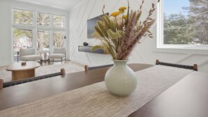 A modern room with a dining table, a vase with dried plants, and a large window. - Steps to Mercedes Benz, Arena, GWCC, Rooftop view (Atlanta)