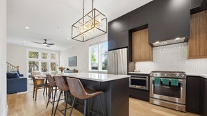 A modern kitchen with a central island, stainless steel appliances, and a bar area. - Steps to Mercedes Benz, Arena, GWCC, Rooftop view (Atlanta)
