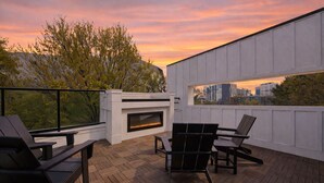 A rooftop terrace with a fireplace, outdoor seating, and a view of the city skyline at sunset. - Steps to Mercedes Benz, Arena, GWCC, Rooftop view (Atlanta)
