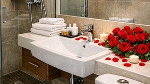 Un bagno moderno con cabina doccia in vetro, lavandino bianco con articoli da toilette e un water.