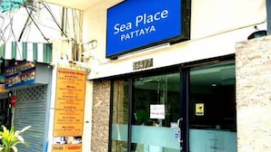 Una vetrina con un cartello blu che riporta 'Sea Place Pattaya' e una lavagna con il menu a sinistra.