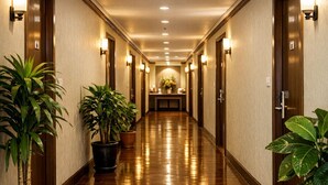 Un corridoio d'hotel con pavimento in legno, piante in vaso e applique.