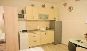 A compact kitchen with a microwave, refrigerator, and sink. There are cabinets above the counter and a small table with a chair. - A 1 cozy studio in the heart of Split with parking (Split)