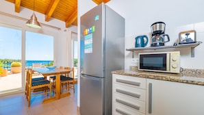 Una cocina equipada con refrigerador, microondas y cafetera, además de un comedor con mesa y sillas.