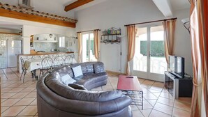 Ein Wohnzimmer mit einer gebogenen Ledersofa, einem Fernseher und einem Essbereich mit Tisch und Stühlen.