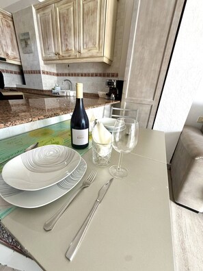 A dining table with a bottle of wine, glasses, cutlery, and a menu. - Sea Views|Canteras beach|1 min walk|Chic (Las Palmas de Gran Canaria)