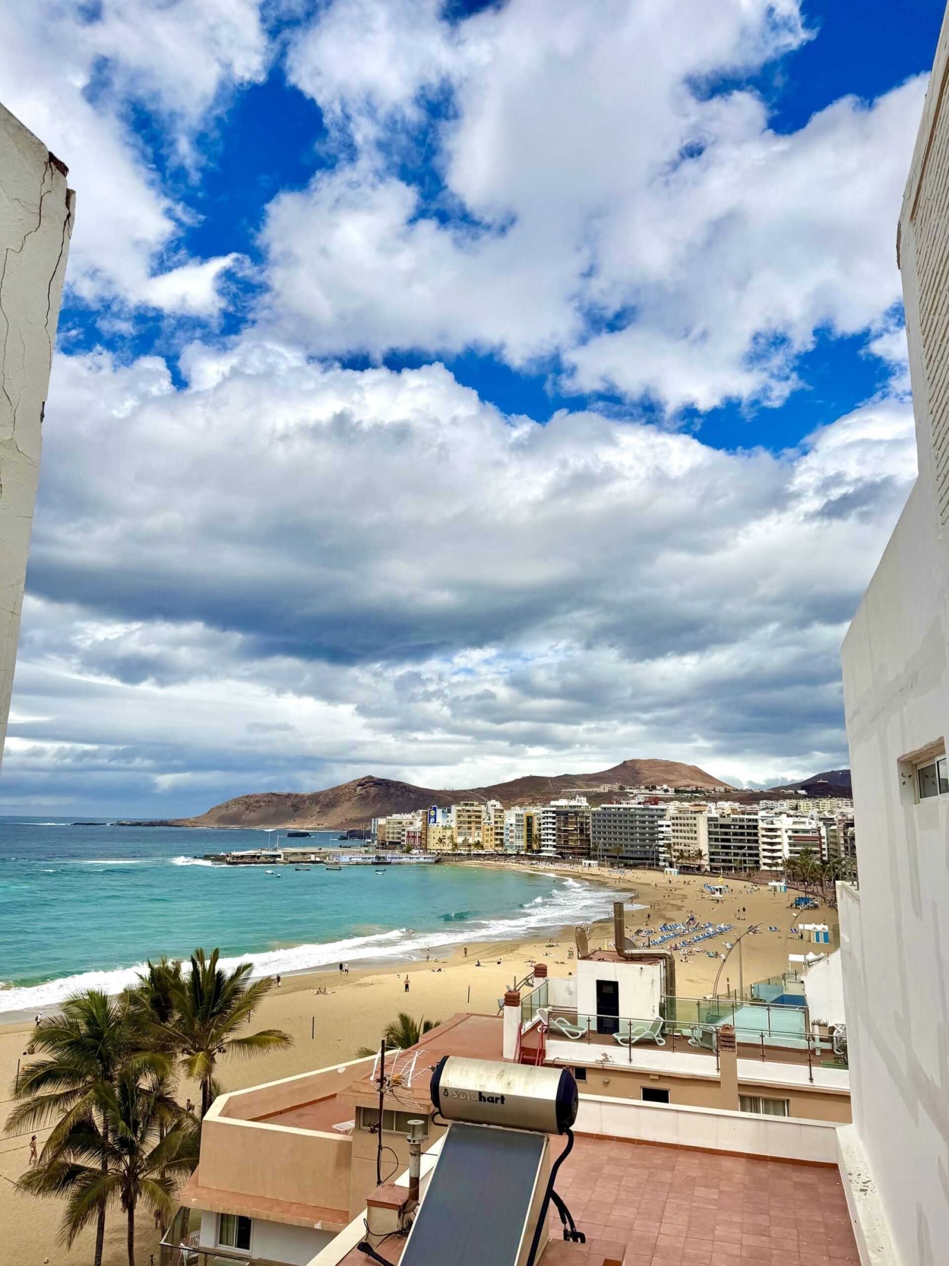 A coastal view with a beach, ocean, and buildings in the background.