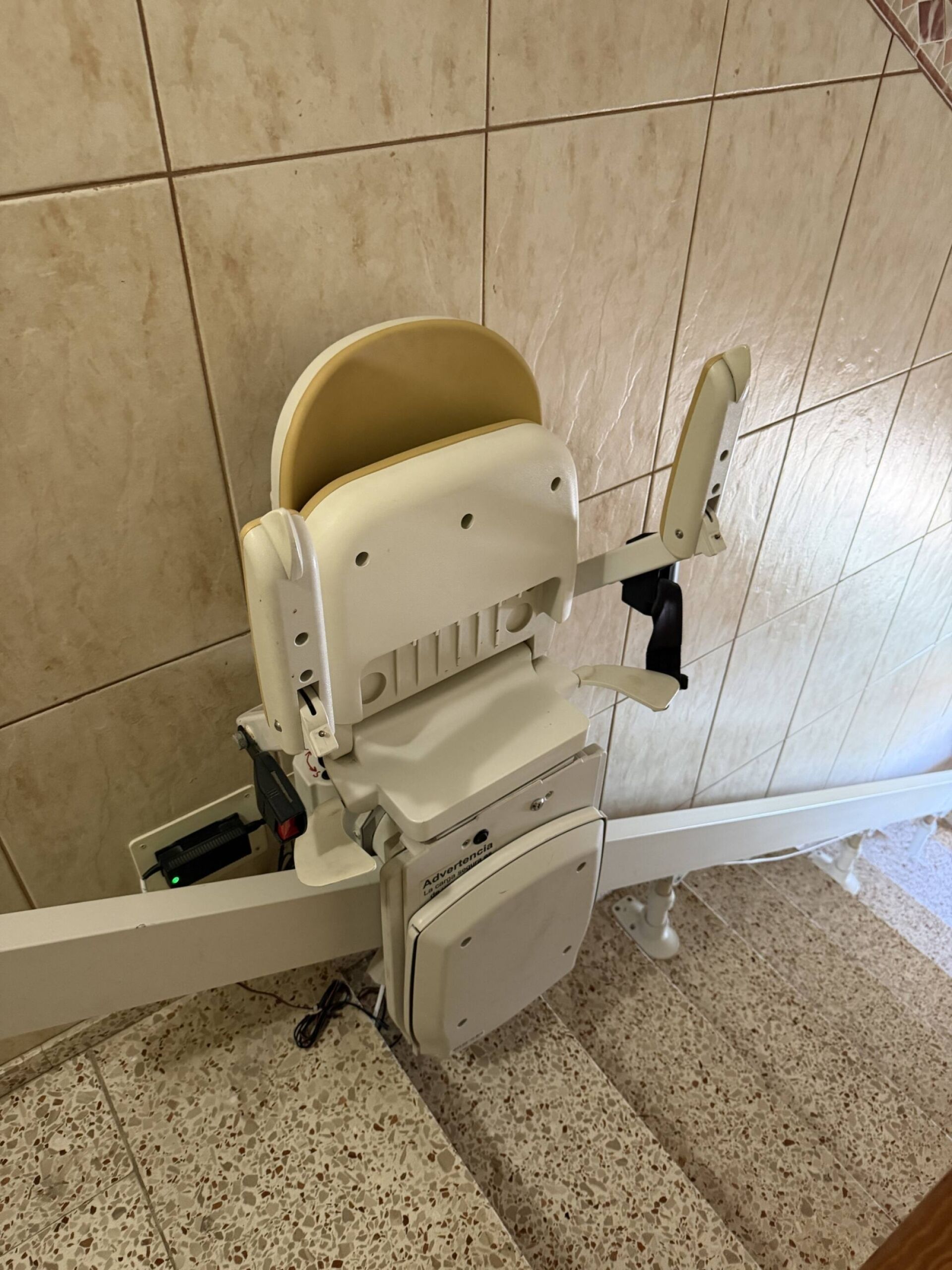 A wheelchair-accessible toilet with a raised seat and a side lever for support.