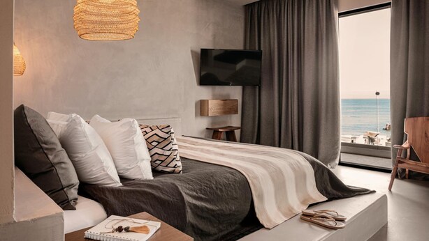 A modern bedroom with a bed, a television, a view of the sea, and a large window. - Cook's Club City Beach Rhodes (Rhodes)