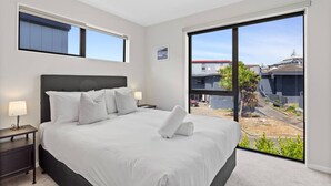 Un dormitorio con una cama grande, dos mesitas de noche y vistas al exterior.