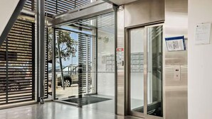 Ein moderner Gebäudeeingang mit Glastür, Metalltreppe und einem Brandschutzschild.