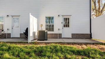 Un edificio blanco con dos puertas, una ventana y un equipo de aire acondicionado.