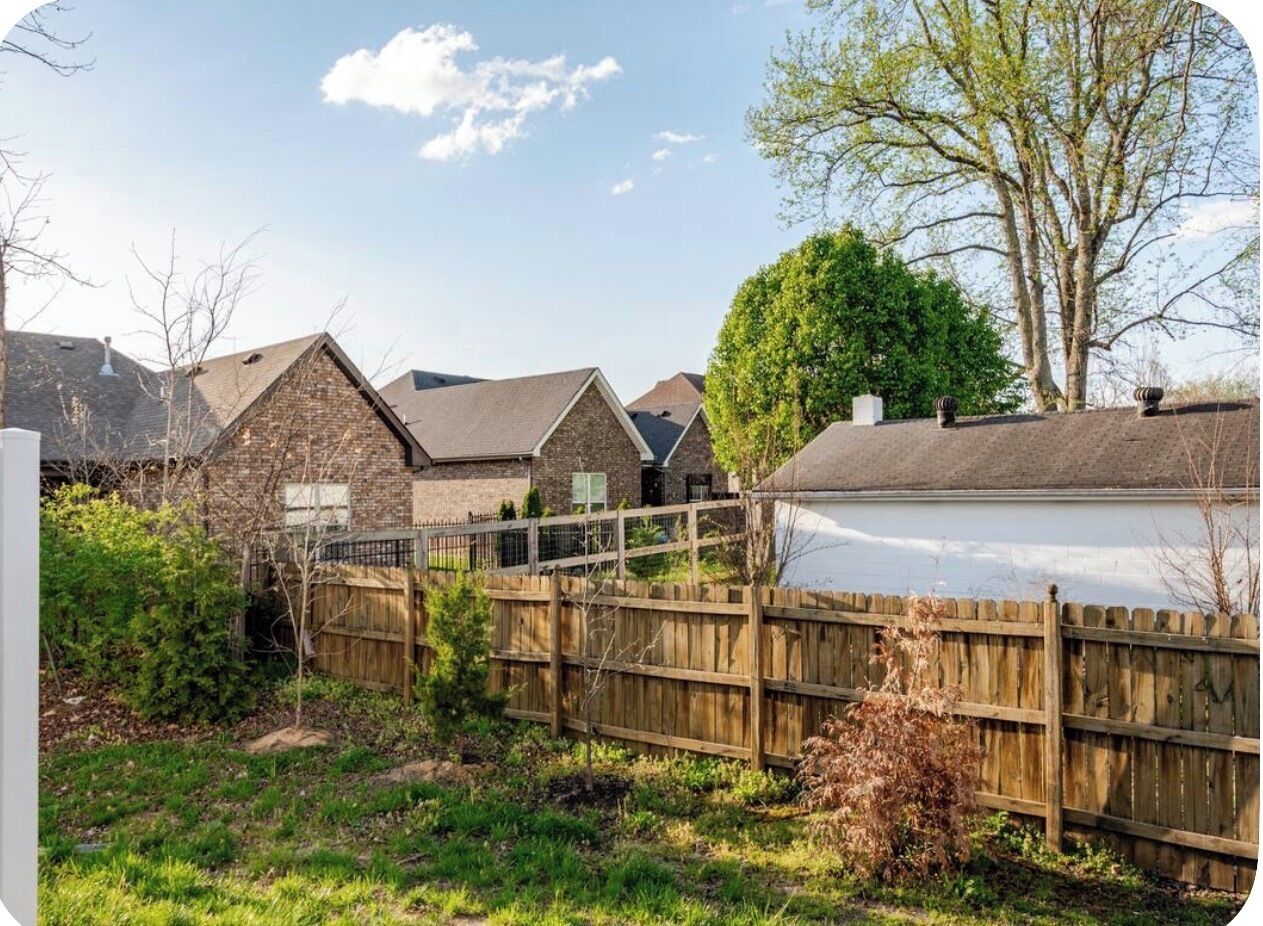 A residential area with houses, a wooden fence, and a tree.