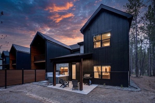 A modern two-story house with a covered patio, a hot tub, and a barbecue area.