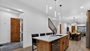 A modern kitchen with a central island, wooden cabinets, and a dining area with a large table and chairs.