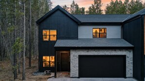 A two-story house with a stone fireplace, a garage, and a driveway.