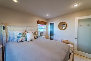 Une chambre à coucher avec un lit, une table de chevet, un miroir et une porte.