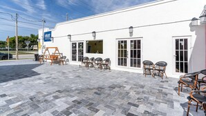 A white building with a tiled patio, outdoor seating, and a sign reading "KRUST." - Cozy 1-bedroom apartment with kitchen in peaceful Tavernier/Key largo (Tavernier)
