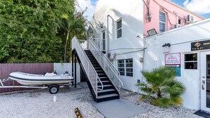 A boat docked outside a building with a staircase leading to a door labeled "ROOM 1". - Cozy 1-bedroom apartment with kitchen in peaceful Tavernier/Key largo (Tavernier)