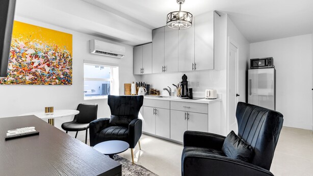 A modern kitchen with white cabinets, a black refrigerator, and a dining area with a black table and two black chairs. - Cozy 1-bedroom apartment with kitchen in peaceful Tavernier/Key largo (Tavernier)