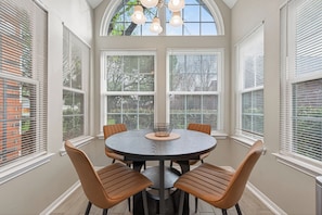A dining area with a round table and six chairs, large windows with blinds, and a ceiling light fixture. - Beautiful 3 bedroom home in peaceful Spring / Cypress area near downtown Houston (Houston)