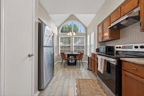 A kitchen with a dining area, wooden cabinets, a stainless steel refrigerator, a microwave, and an oven. - Beautiful 3 bedroom home in peaceful Spring / Cypress area near downtown Houston (Houston)