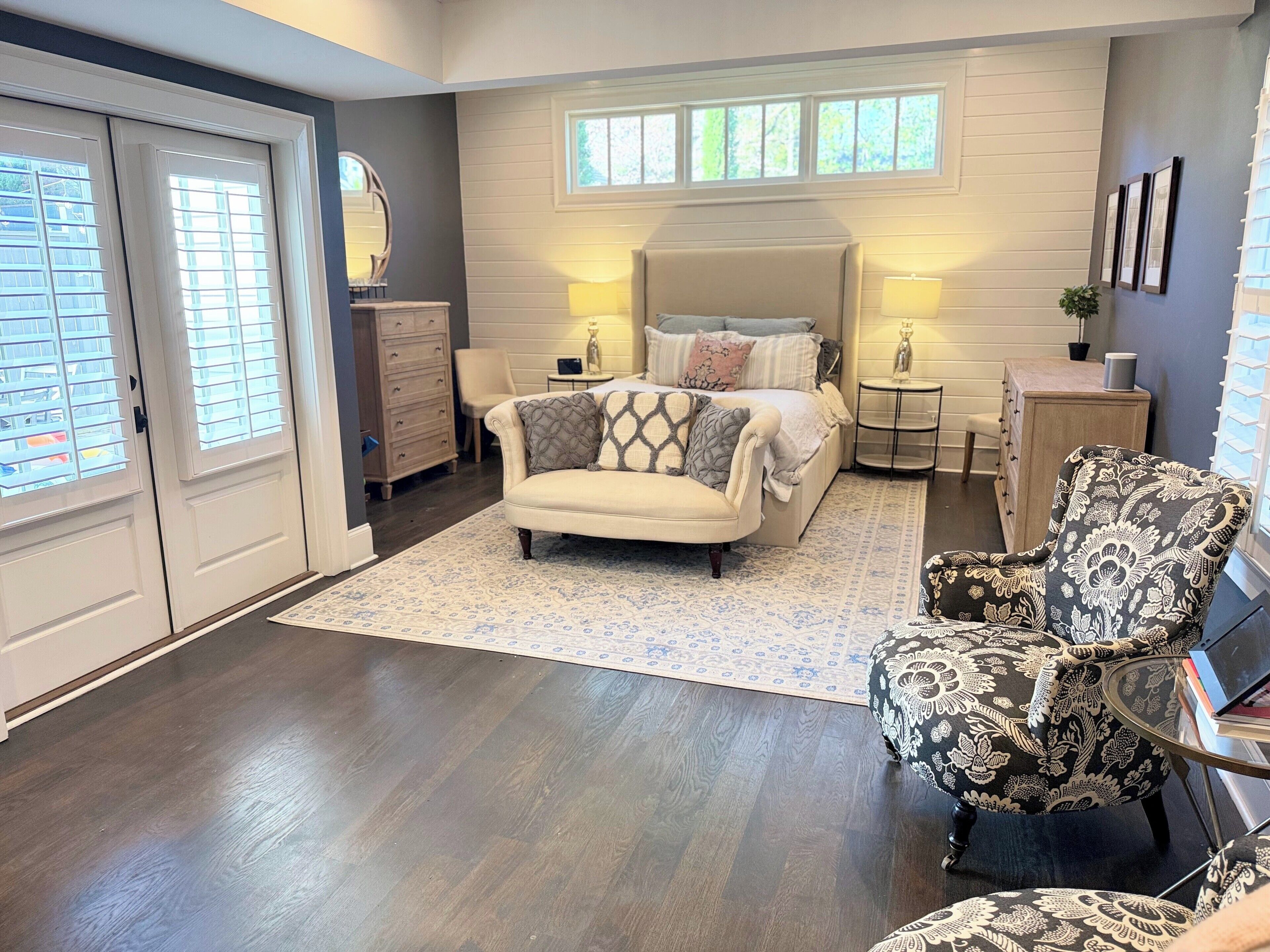 A bedroom with a bed, a chair, a dresser, a nightstand, and a window.